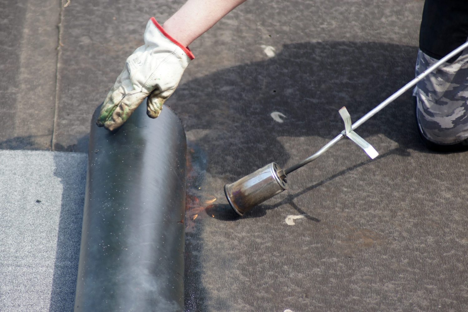 The flat roof installation with propane blowtorch during construction works with roofing felt