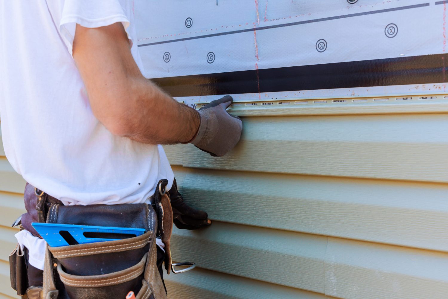 Handyman process installing vinyl PVC siding during construction on facade new home