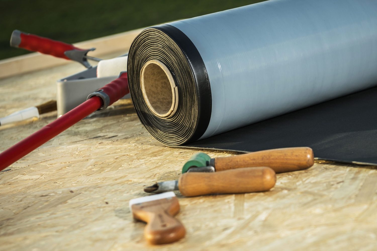 Roll of Modern EPDM Roofing Rubber Material and Some Tools. Roof Job Theme.